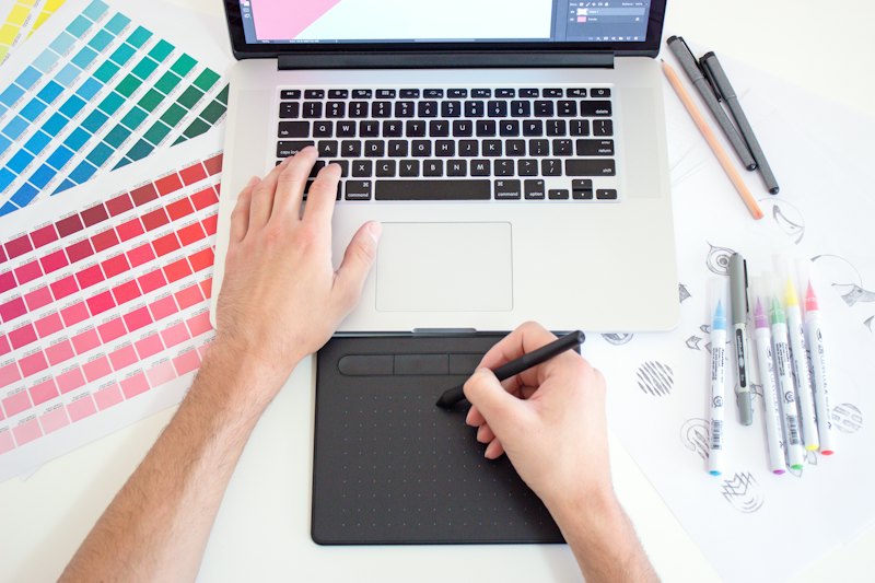 Projektant pracuje na tablecie graficznym obok palety kolorów